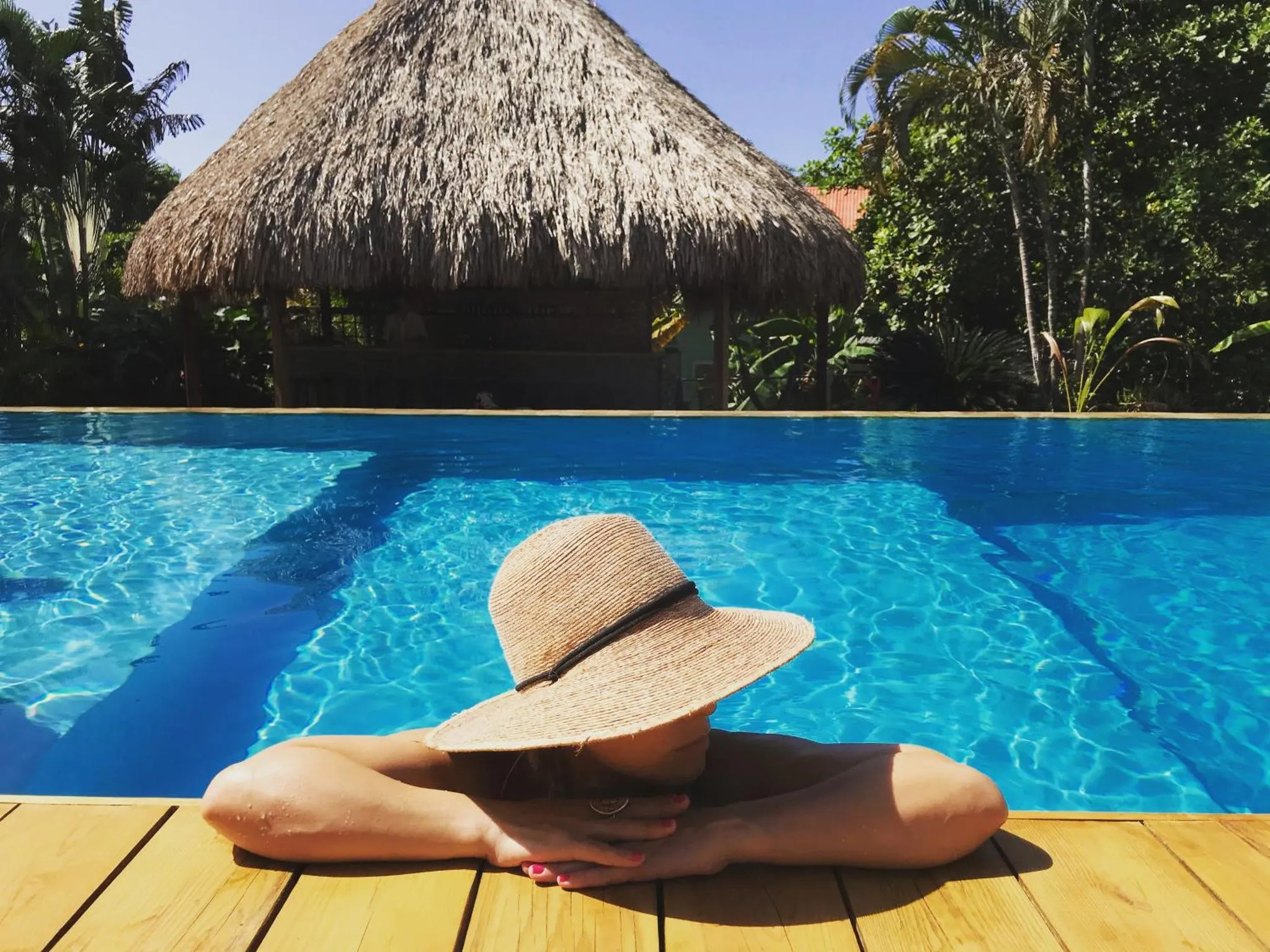 Une personne se détend au bord d'une piscine ensoleillée.