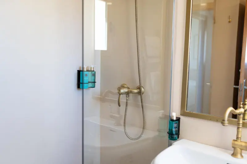 Douche à l'italienne avec pommeau et robinetterie dorées.