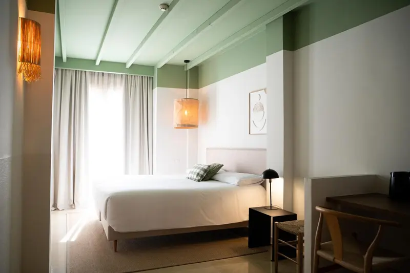 Une chambre lumineuse avec un lit blanc et des murs bicolores.