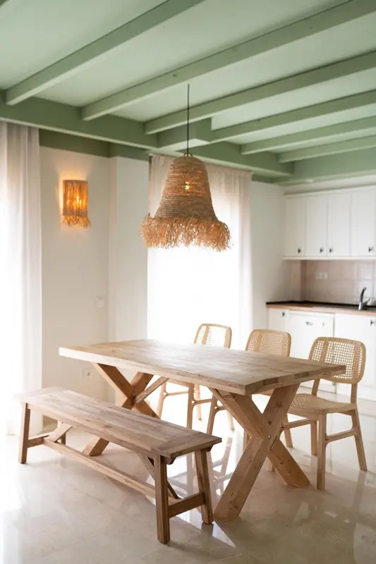 Une table en bois clair et des chaises dans une salle à manger lumineuse.