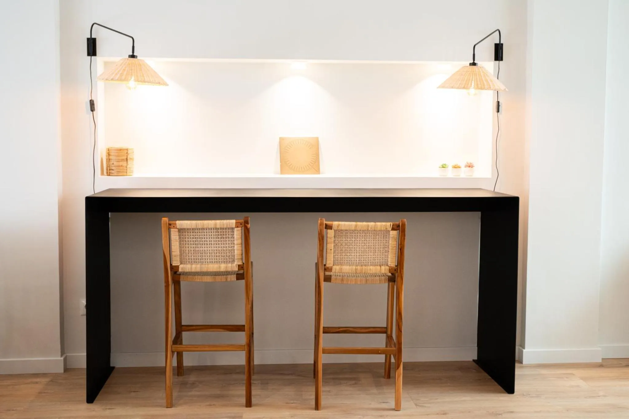 Un comptoir noir est accompagné de deux tabourets en bois clair.