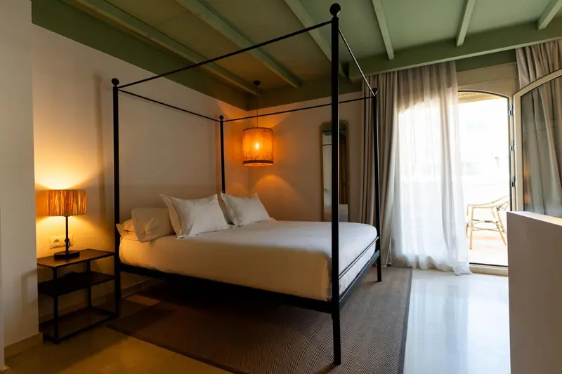 Une chambre avec un lit à baldaquin et une fenêtre ouverte sur l'extérieur.