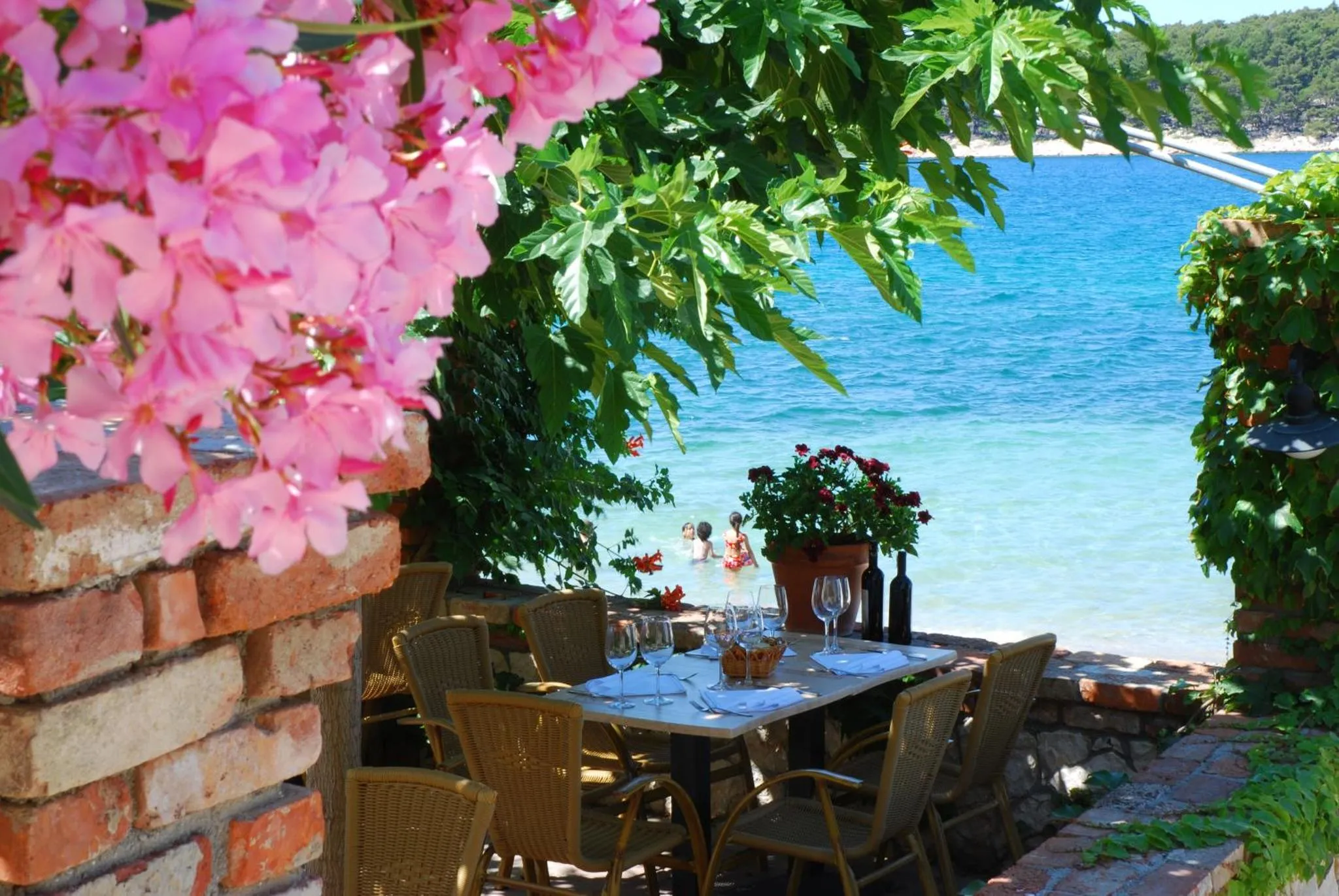 Une table est dressée sur une terrasse ensoleillée avec vue sur la mer.
