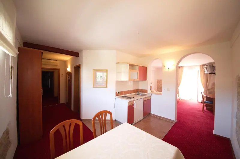 Une salle à manger lumineuse avec une table et des chaises, donnant sur une kitchenette et un espace salon.