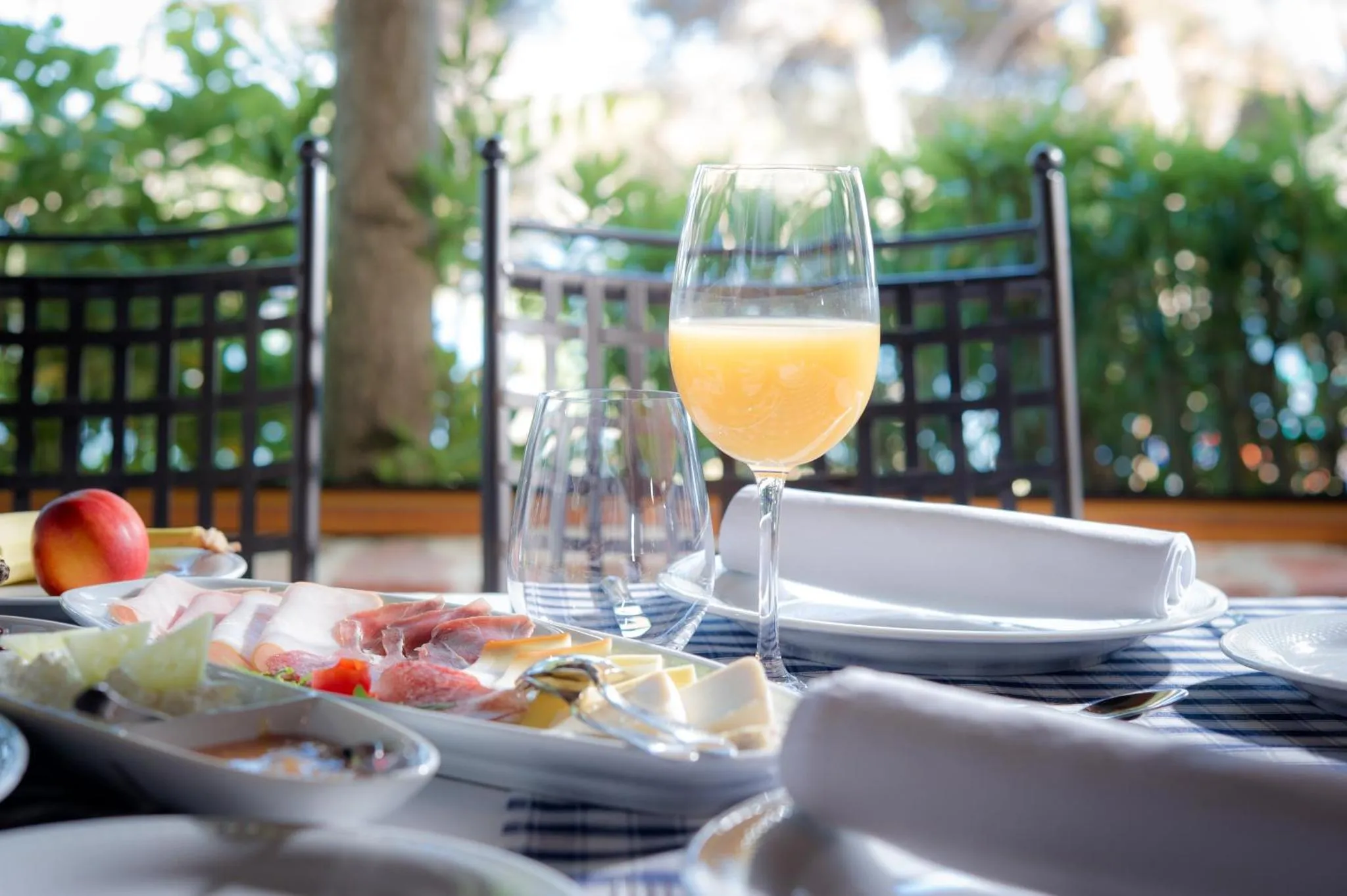 Une table dressée avec un petit-déjeuner composé de charcuterie, de fromage et de jus d'orange.