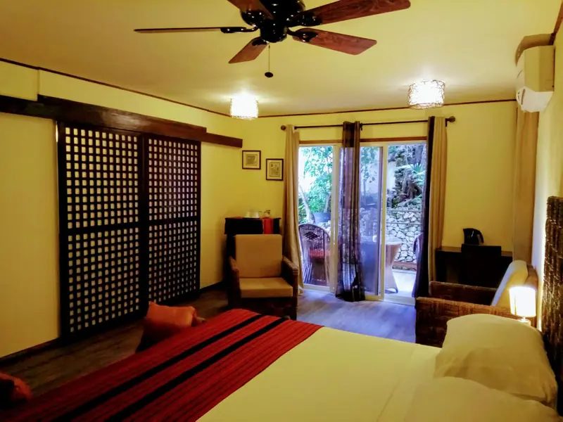 Une chambre lumineuse avec un lit rouge et un accès à une terrasse.