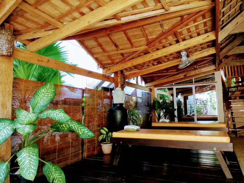 Espace de massage en bois avec table et plantes tropicales.
