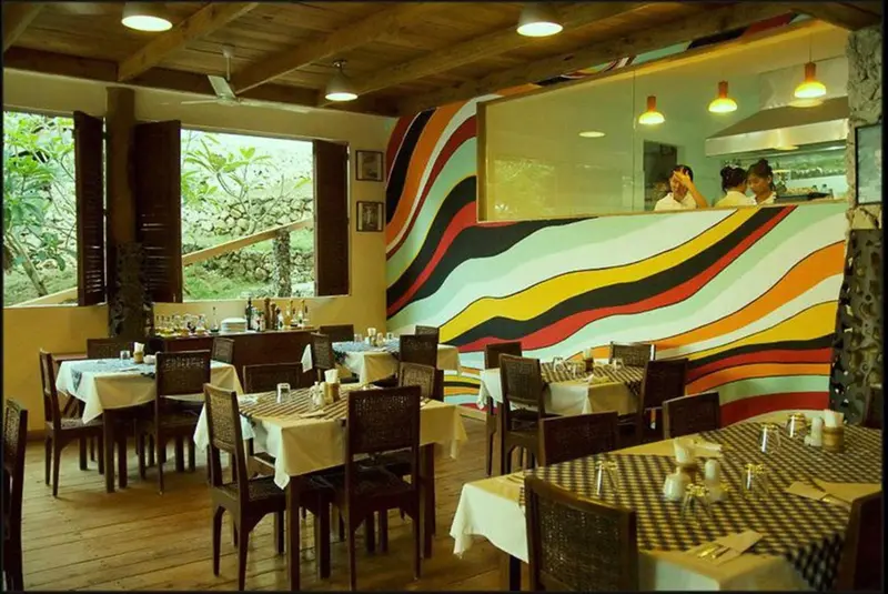 Une salle de restaurant lumineuse avec des tables nappées et un décor mural coloré.