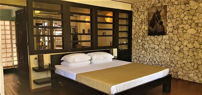Une chambre avec un grand lit et un mur en pierre.