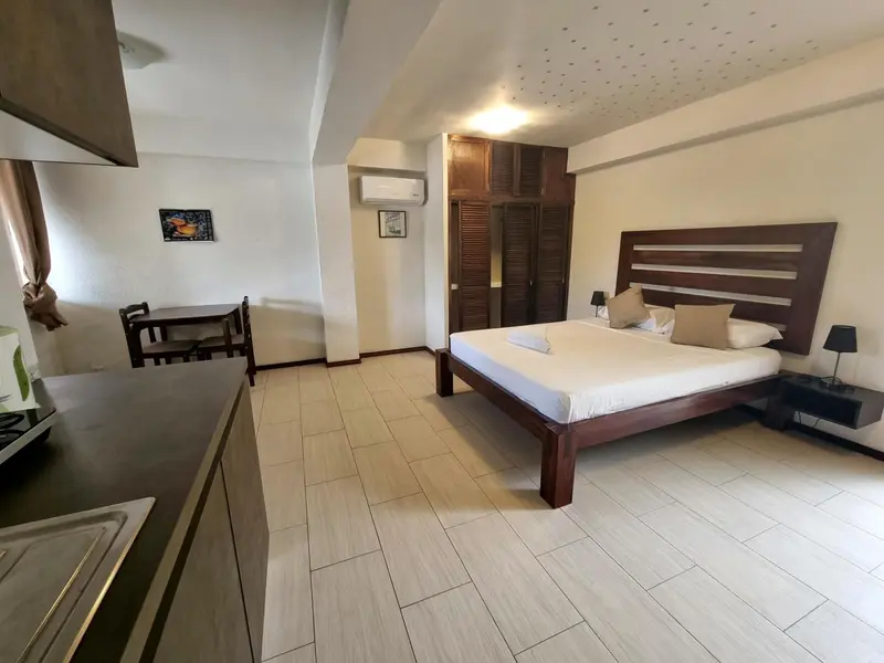 Une chambre lumineuse avec un lit double et un coin repas.