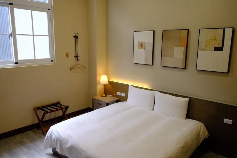 Une chambre lumineuse avec un lit double et des tableaux décoratifs.