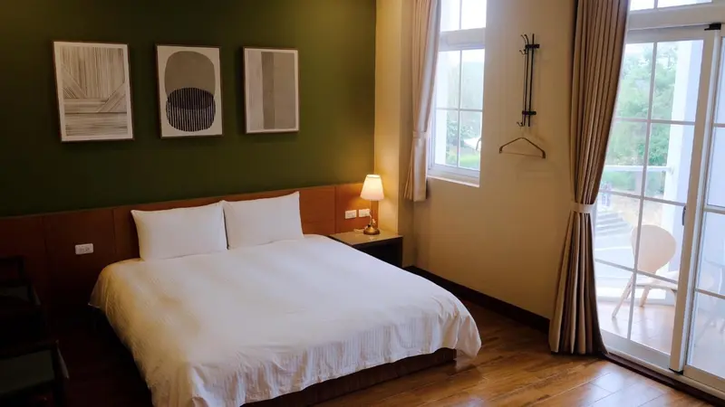 Une chambre lumineuse avec un lit blanc et une vue sur l'extérieur.