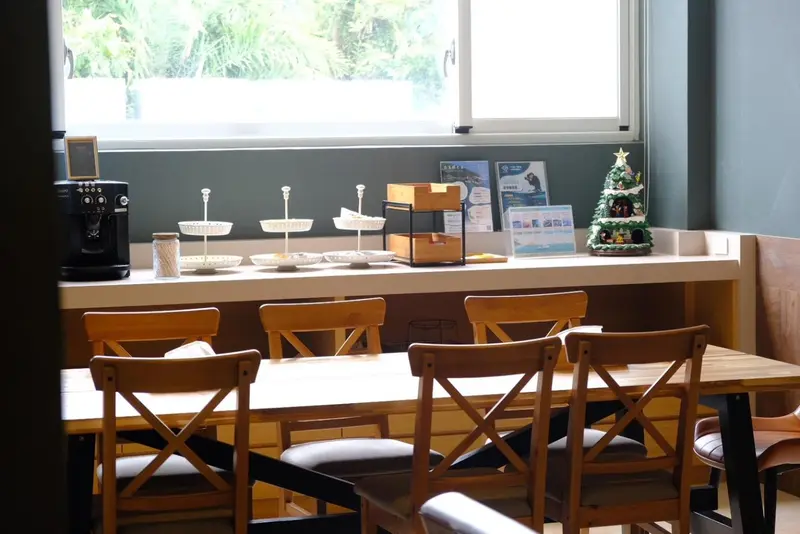 Une table en bois est entourée de chaises dans une salle lumineuse.