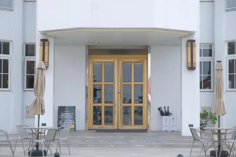 Entree d'un batiment avec un auvent et des tables de terrasse.