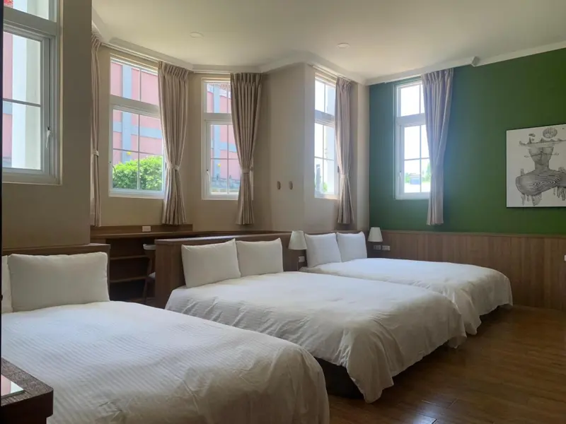 Une chambre lumineuse avec deux lits doubles et des rideaux beiges.