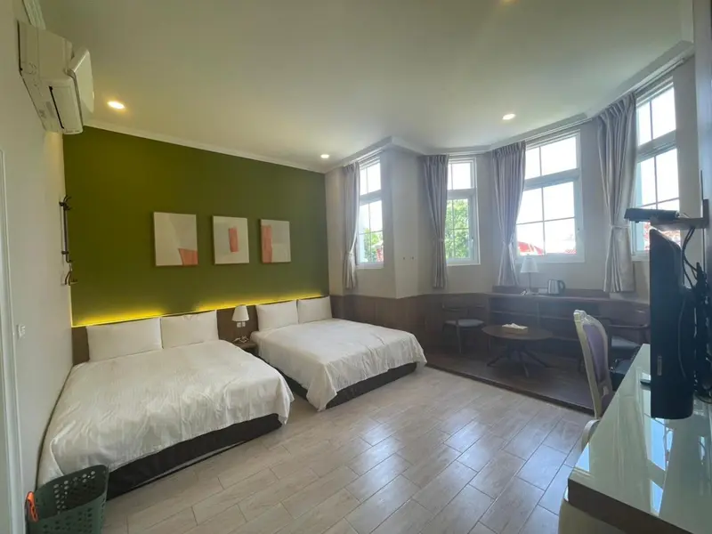 Une chambre lumineuse avec deux lits et un coin repas près des fenêtres.