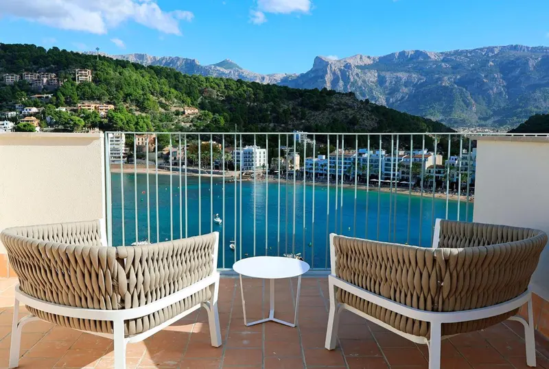 Terrasse avec mobilier d'extérieur donnant sur une baie et des montagnes.