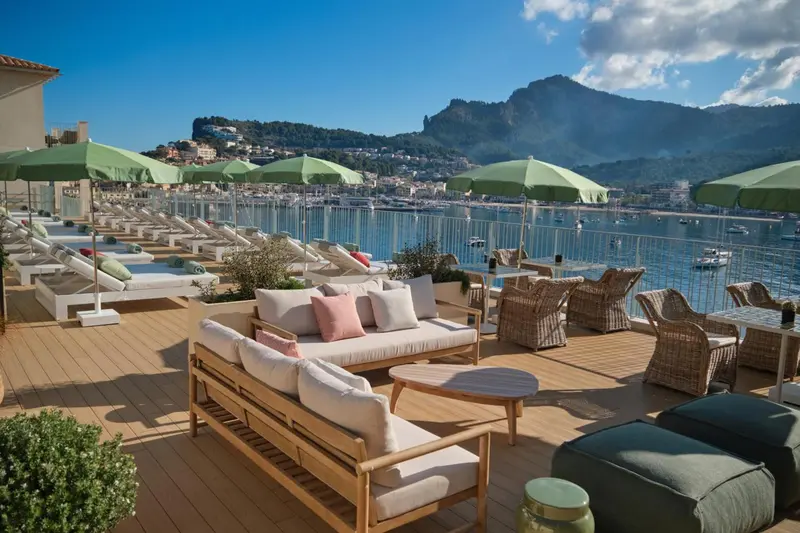 Terrasse aménagée avec canapés, chaises longues et tables basses face à la mer.