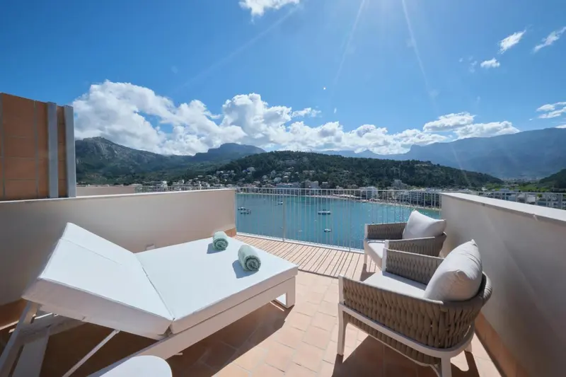 Terrasse aménagée avec chaises longues et vue sur la mer et les montagnes.