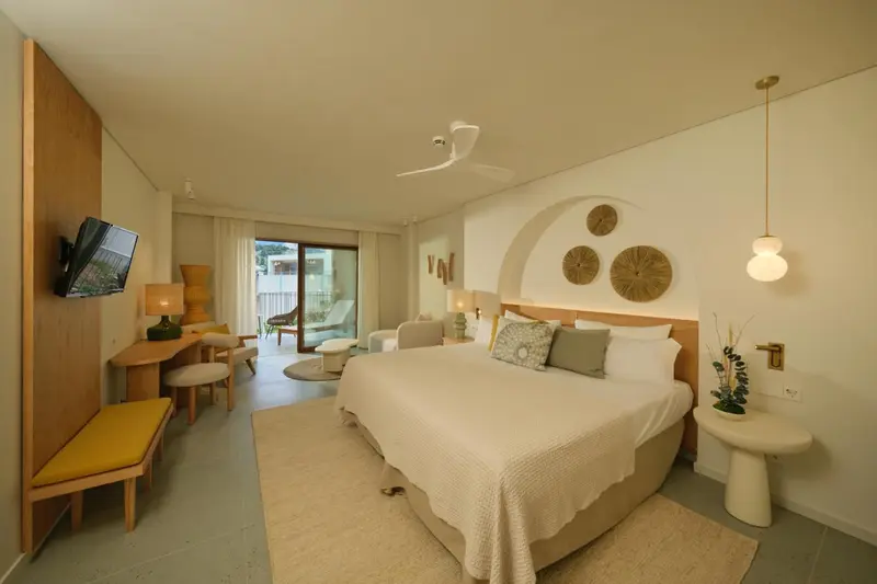 Une chambre lumineuse avec un grand lit et un coin salon.
