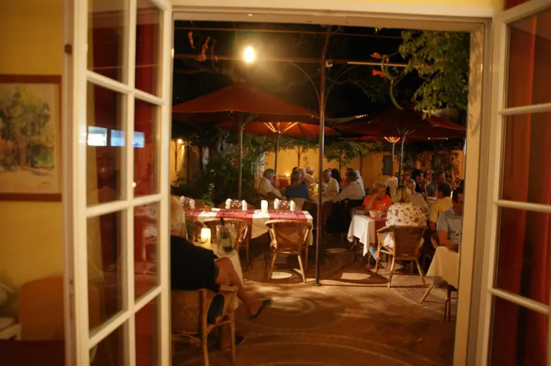 Une salle à manger extérieure éclairée par des parasols rouges et des bougies.