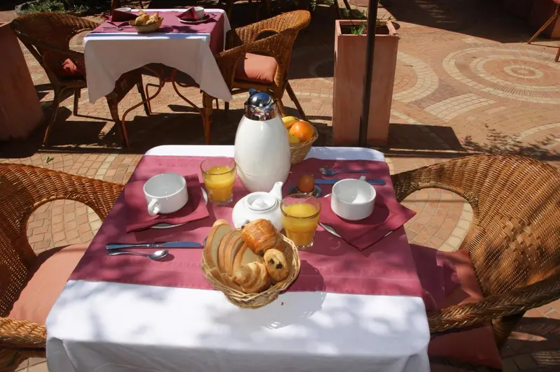 Une table est dressée pour le petit-déjeuner avec des viennoiseries et des jus d'orange.