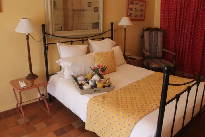 Une chambre lumineuse avec un lit recouvert d'une courtepointe jaune et d'oreillers blancs.