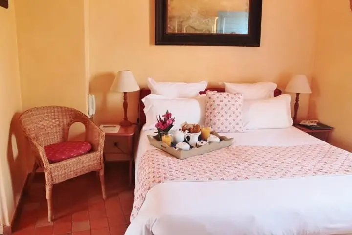 Un lit préparé avec un plateau de petit-déjeuner et une chaise en osier dans une chambre.