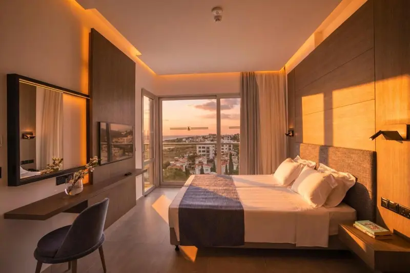 Une chambre lumineuse avec un grand lit et une vue sur le coucher de soleil.
