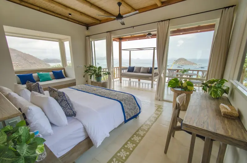 Une chambre lumineuse s'ouvre sur une terrasse avec vue sur la mer.