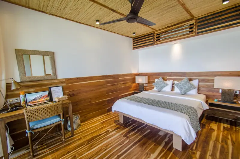 Une chambre lumineuse avec un lit double et un bureau en bois.