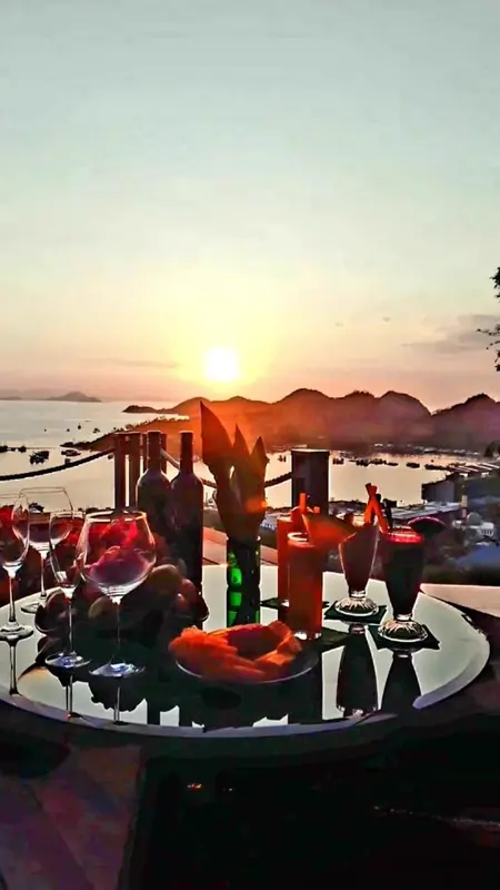 Une table dressée avec des verres et des bouteilles au coucher du soleil en bord de mer.