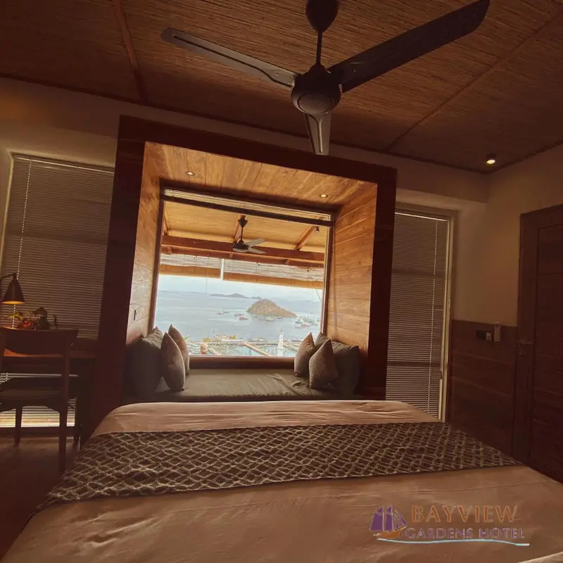 Une chambre avec un grand lit face à une baie vitrée donnant sur la mer.