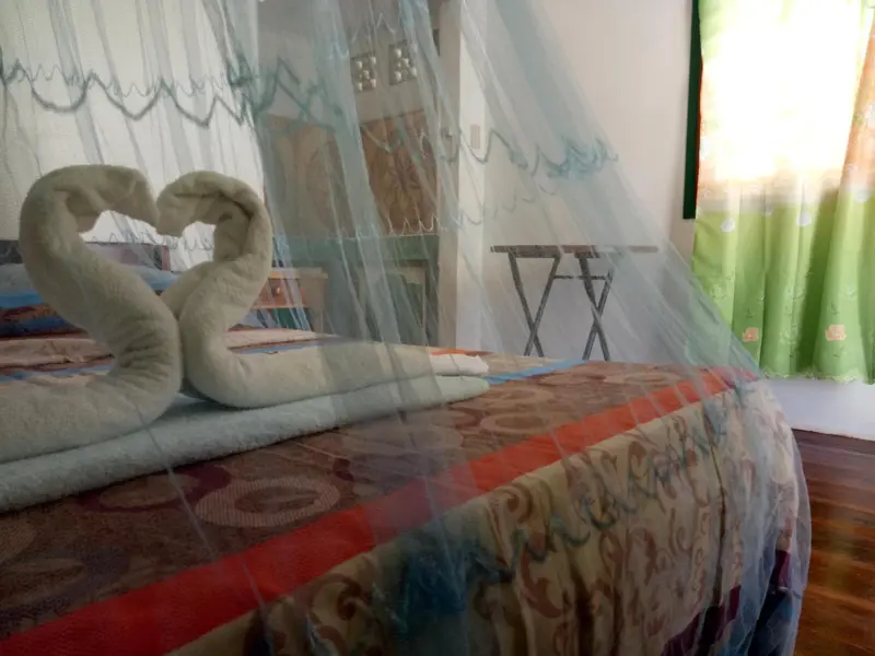 Un lit recouvert d'une courtepointe colorée et décoré de serviettes en forme de cygnes se trouve dans une chambre.