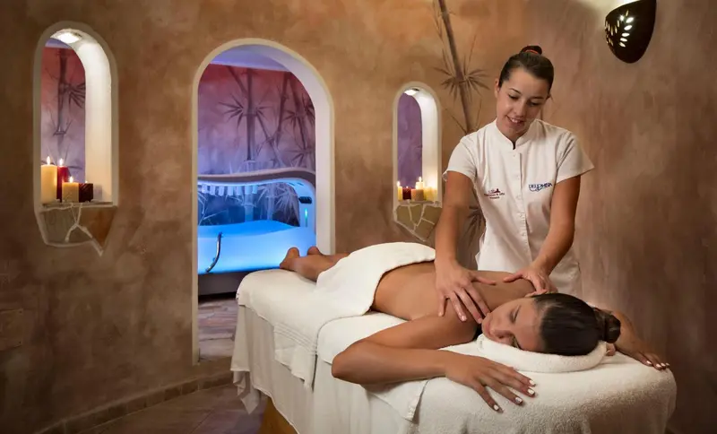Une femme reçoit un massage sur une table dans une salle lumineuse et décorée.