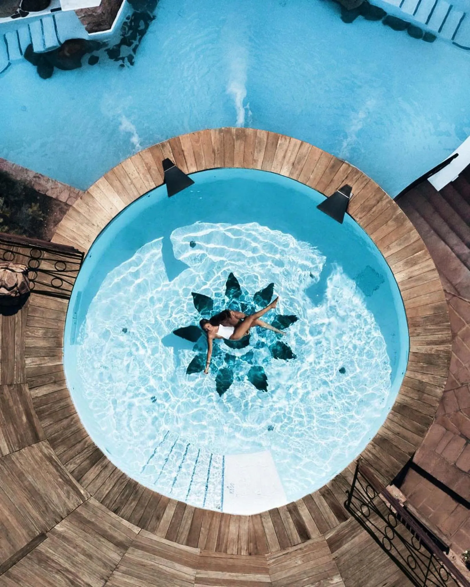 Une personne se détend dans une piscine ronde au bord d'une terrasse.