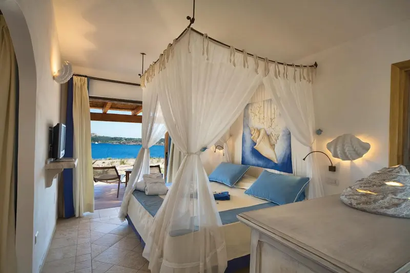 Une chambre lumineuse avec un lit à baldaquin donnant sur la mer.