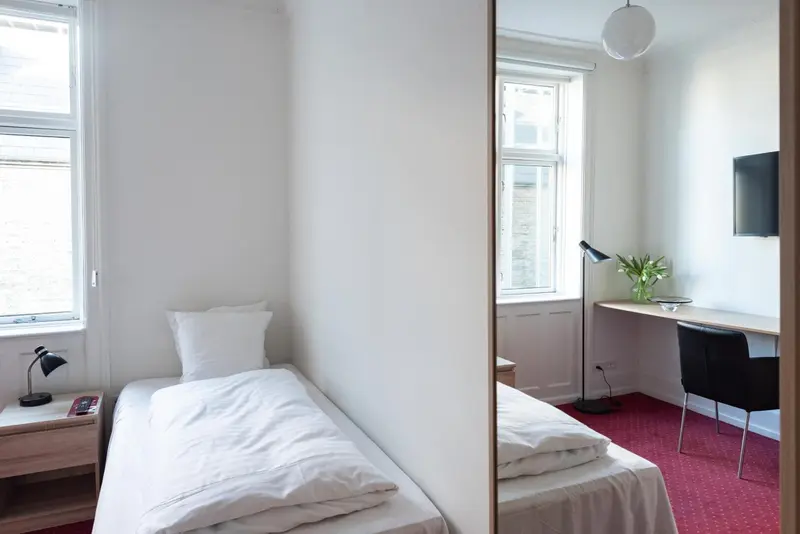 Une chambre lumineuse avec un lit simple et un bureau.