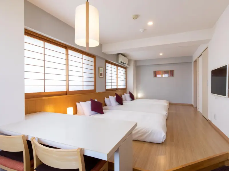 Une chambre lumineuse avec des lits jumeaux et une table.