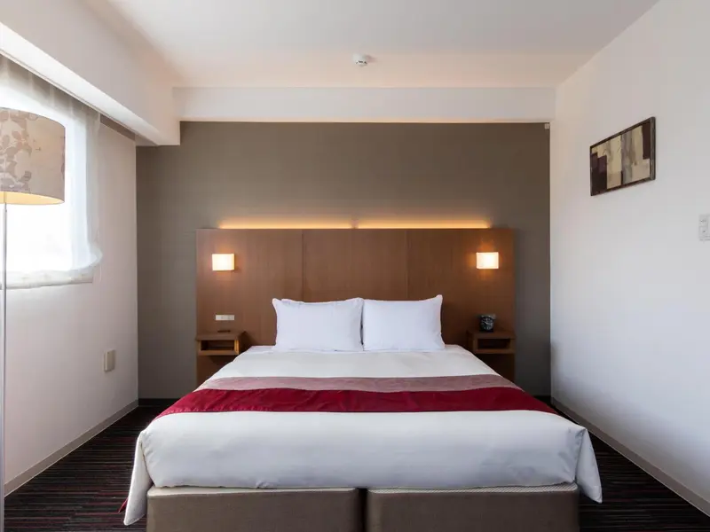 Une chambre avec un grand lit recouvert d'une courtepointe blanche et rouge.