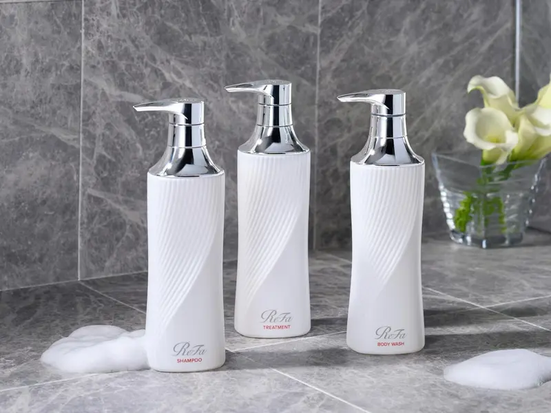 Trois distributeurs de produits de toilette sur un comptoir gris.