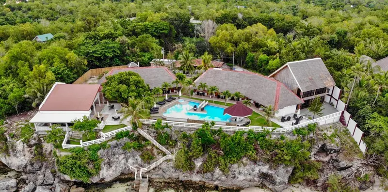 Vue aérienne d'un complexe hôtelier avec piscine et végétation luxuriante.