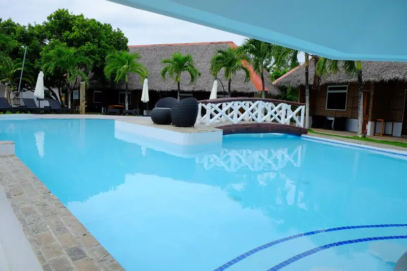 Une piscine turquoise bordée d'une terrasse ensoleillée.