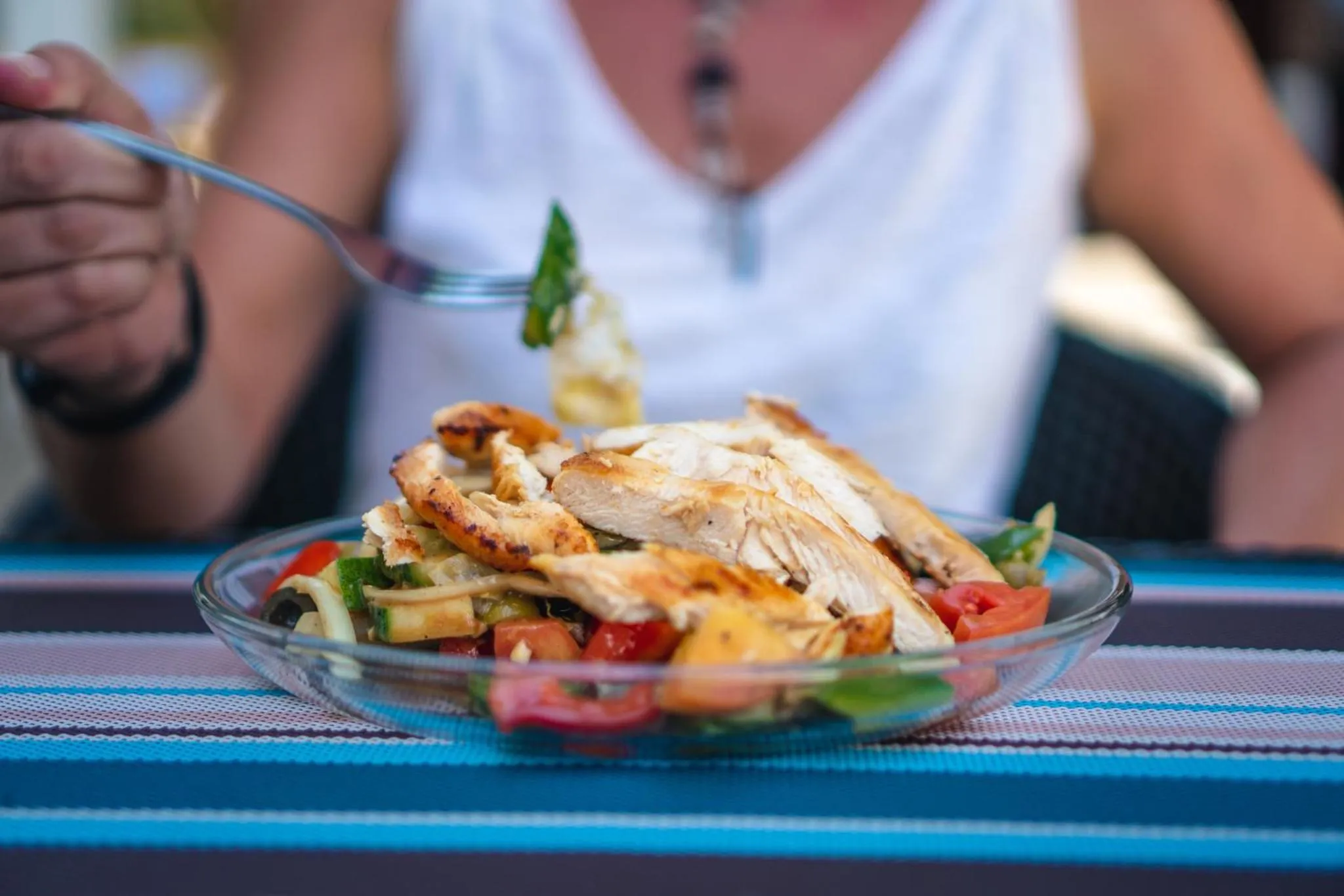 Une personne déguste une salade colorée à l'assiette.