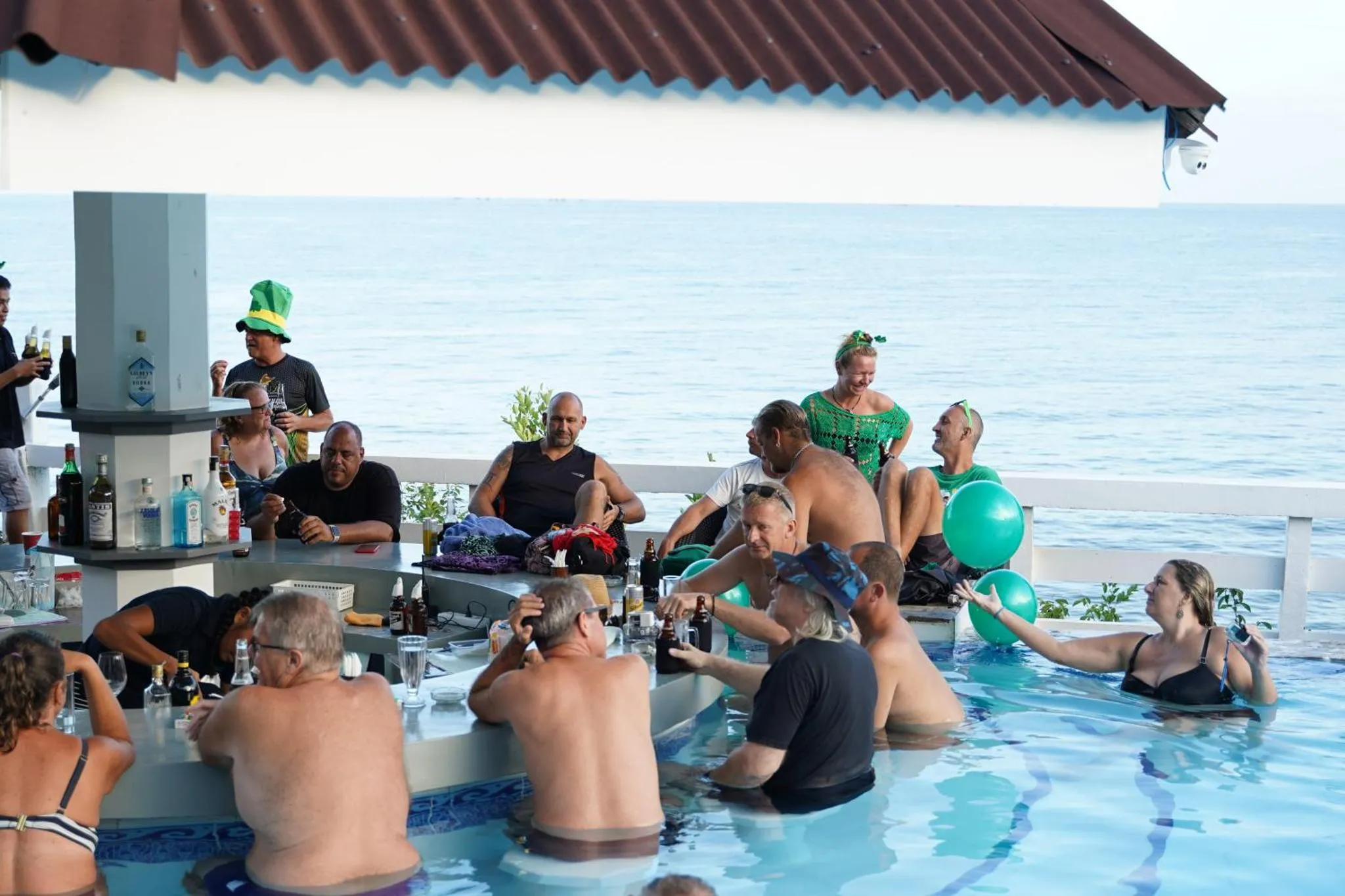 Un groupe de personnes se détend autour d'un bar dans une piscine en bord de mer.