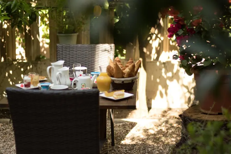 Une table de petit-déjeuner est dressée sur une terrasse ensoleillée.
