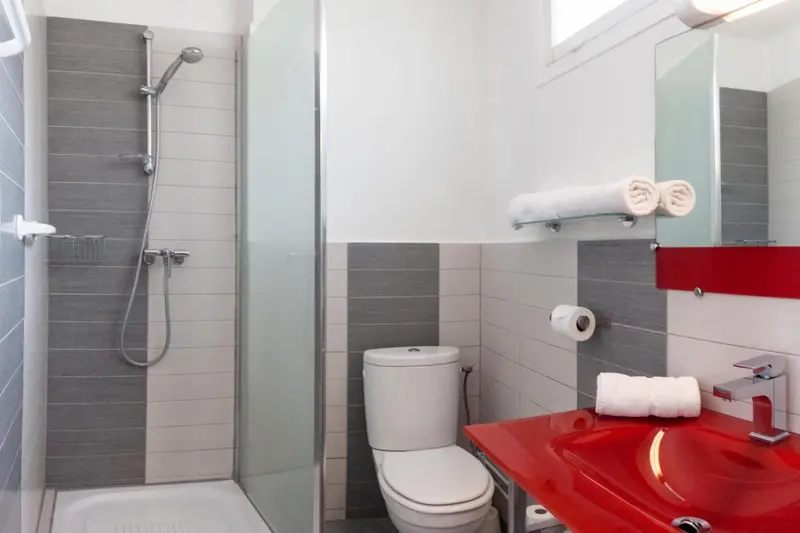 Une salle de bain moderne avec douche à l'italienne et lavabo rouge.