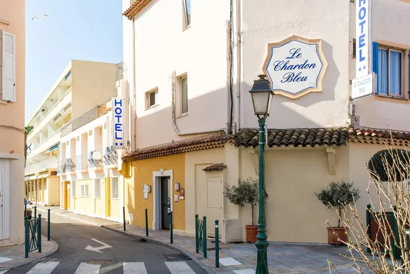 Façade d'un bâtiment jaune avec des balcons et une enseigne lumineuse.