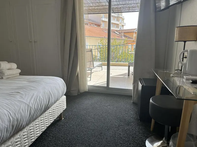 Une chambre avec un lit et un bureau donnant sur une terrasse.