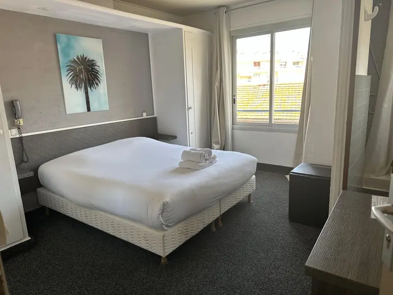 Une chambre lumineuse avec un grand lit et un accès à une terrasse.